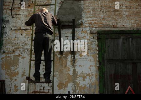 Homme dans les escaliers. L'homme monte sur le toit. Le travailleur descend. Inspection du toit du bâtiment. Banque D'Images