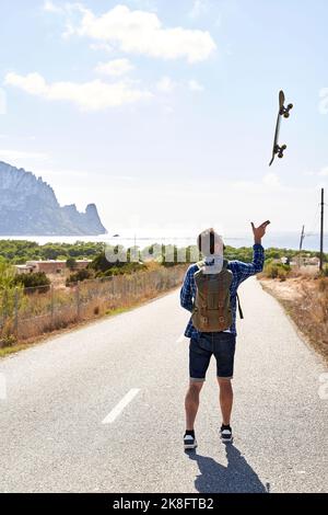 Backpacker lance une planche à roulettes par beau temps Banque D'Images