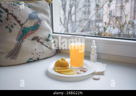 Froid de saison : verre avec vitamine C liquide, citron en tranches, pilules instantanées et vaporisateur nasal avec serviettes en papier sur le rebord de la fenêtre. À côté de la vintage Banque D'Images