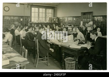 Original début des années 1900, carte postale de l'époque WW1 de jeunes employés de bureau, commis d'administration, comptes/ administration avec des travailleurs de sexe masculin et féminin dans un grand bureau occupé et exigu, beaucoup de paperasserie. Royaume-Uni vers 1913 Banque D'Images