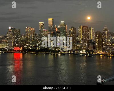 La pleine lune s'élève au-dessus de la ligne d'horizon le long du long Island City Astoria Waterfront de l'East River à Queens, New York. Banque D'Images