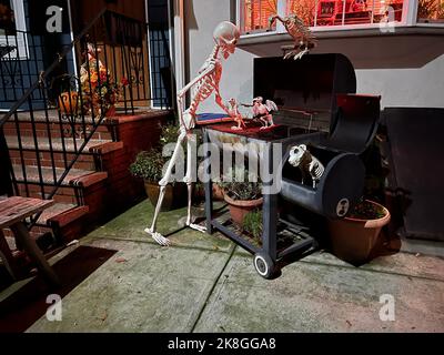 Squelette d'Halloween freaky ayant un barbecue dans la cour d'une maison sur une rue résidentielle à Brooklyn, New York. Banque D'Images