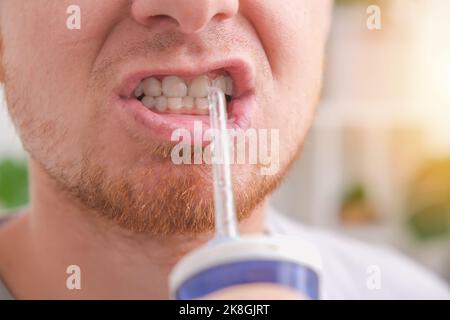 Un beau homme nettoie sa bouche et ses dents avec un irrigateur électrique blanc en gros plan le matin. Banque D'Images