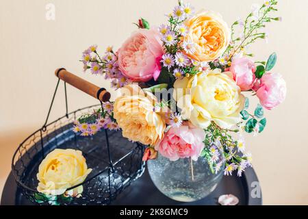 Bouquet frais de fleurs roses mis dans un vase en verre sur la table. Gros plan des fleurs jaunes roses avec panier. Décoration d'été Banque D'Images