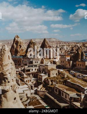 Paysages étonnants de cheminées de fées massives et maisons traditionnelles âgées situées dans la vallée montagneuse contre ciel bleu ciel nuageux le jour ensoleillé en Cappadoce Banque D'Images