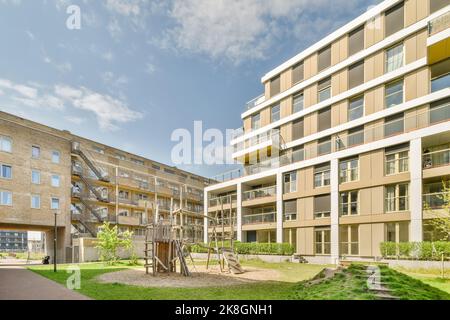 Aire de jeux pour enfants d'une zone communautaire de bâtiments sous un ciel bleu avec des nuages Banque D'Images