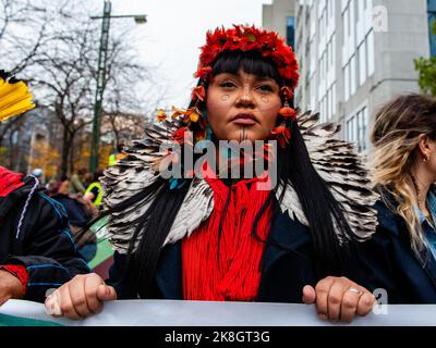 Une femme autochtone est vue porter des plumes rouges et de la peinture indigène traditionnelle sur son visage pendant la marche climatique. Des milliers de personnes se sont rassemblées à la gare de Bruxelles-Nord pour protester contre le manque d'action sur la crise climatique, lors d'une marche sur le climat organisée par la Climate Coalition (une organisation nationale à but non lucratif qui réunit plus de 90 organisations autour du thème de la justice climatique). Avec ce mois de mars, ils exigent de combattre la crise énergétique par une politique énergétique unique entre les régions et l'État fédéral qui permet à la Belgique d'atteindre 100% d'énergie renouvelable avant 20 Banque D'Images