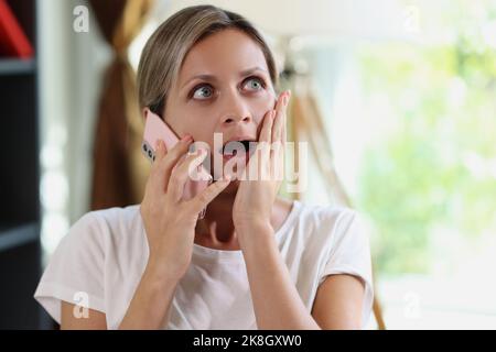 Femme surprise et choquée parlant au téléphone Banque D'Images