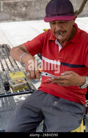 artisan dans la rue faisant des figurines de vélo avec fil, fait main métal figurines mexique Banque D'Images