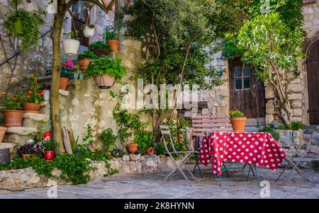 Chaises et table avec nappe rouge dans une petite place dans le village médiéval des Matelles dans le sud de la France (Herault) Banque D'Images