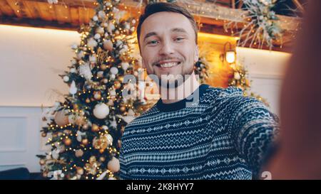 Portrait d'un jeune homme beau faisant un appel vidéo en ligne le jour de Noël parlant tenant la caméra appréciant la communication Internet. Concept de personnes et de vacances. Banque D'Images