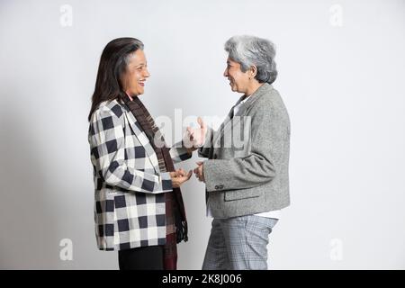 Deux femmes d'affaires indiennes âgées matures collègues ou collègues amis riant isolés sur fond blanc. Bonne asiatique 60s à cheveux gris femme bourreau Banque D'Images