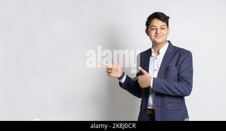 Portrait du jeune adolescent indien heureux garçon montre espace vide pour votre promotion, isolé sur fond blanc studio, doigt de pointage pour l'annonceur Banque D'Images