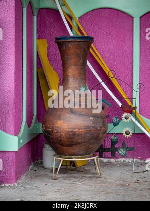 Un grand vase à fleurs est dans un coin avec quelques objets à jeter Banque D'Images