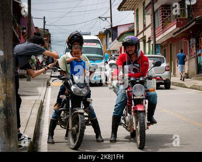 Filandia, Quindio, Colombie - 5 juin 2022: Une femme prend une photo de deux hommes colombiens sur un Motos avec un petit enfant en attente de la signalisation Banque D'Images