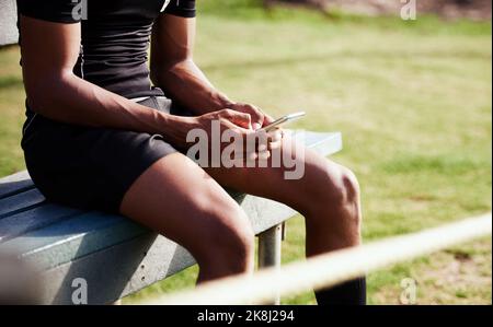 A manqué les statistiques Voir les statistiques au format mobile. Un homme assis sur un banc et utilisant un smartphone à un match de rugby. Banque D'Images