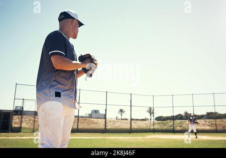 Un jeune homme qui pitche une balle pendant un match de baseball. Banque D'Images