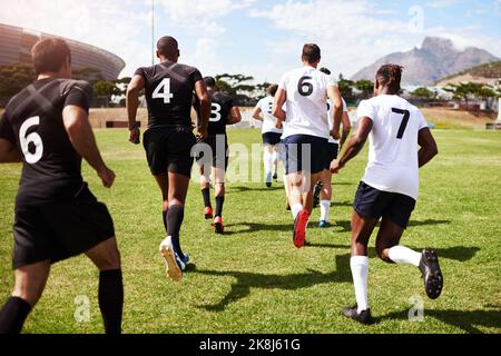 Les gagnants sont arrivés. Un groupe de jeunes joueurs de rugby se lançant sur le terrain pendant un match. Banque D'Images