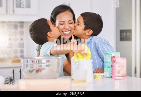 Heureux, mère et enfants embrassant la joue pour l'amour, la pâtisserie et la fête de la mère dans la cuisine à la maison. Mama sourire avec les petits garçons dans joyeuse Banque D'Images