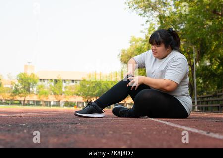 Femme asiatique en surpoids une nouvelle douleur de cheville de coureur pendant la course, accident d'entraînement de coureur d'athlète. Sport courir la cheville entortillée entorse cause des blessures. wei Banque D'Images