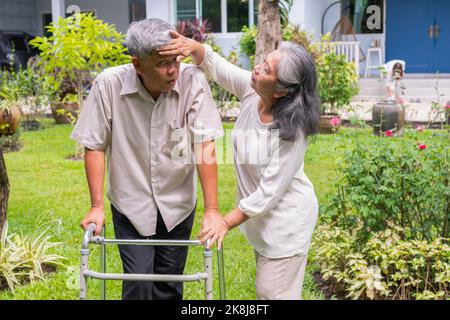 Un vieil homme asiatique heureux utilise un marcheur et marche dans l'arrière-cour avec sa fille et sa femme. Concept de la retraite heureuse avec les soins d'un foyer Banque D'Images