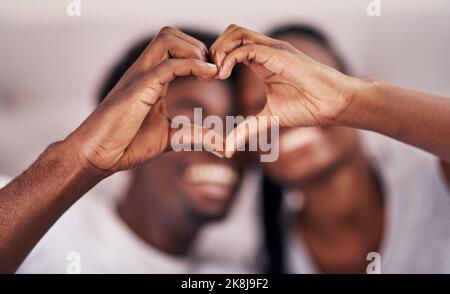 L'amour vit ici. Un jeune couple formant un coeur en joignant leurs mains. Banque D'Images