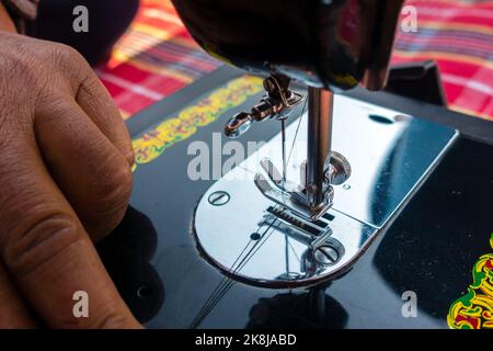 février 12th 2022, Dehradun City Inde. Main fonctionnement manuel machine à coudre aiguille avec fil. Banque D'Images