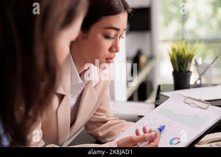 Les employés analysant les statistiques des rapports financiers sur le presse-papiers, la femme pointant vers des graphiques sur des documents. Démarrer les travailleurs en planifiant la stratégie d'affaires, en discutant des résultats de la recherche de l'entreprise Banque D'Images