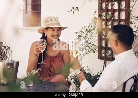 Un week-end est exactement ce dont nous avions besoin. Un jeune couple heureux qui profite d'un verre de vin tout en s'asseyant dehors. Banque D'Images