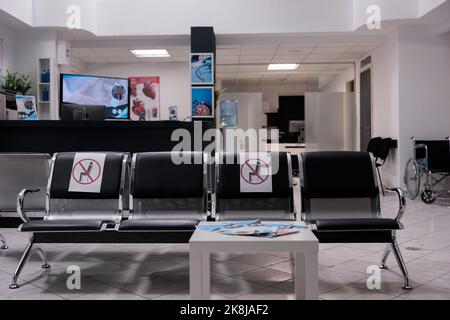 Photo générale de l'aire d'attente de l'hôpital vide. Sièges sectionnés pour prévenir l'infection covid 19 à aucun bureau de professionnels de la santé de personnes. Hall d'accueil de la clinique médicale inoccupée. Banque D'Images