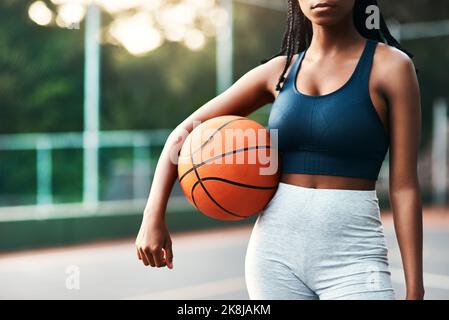 Je ne suis rien sans le basket-ball. Une sportswoman méconnaissable debout sur le court seul et tenant un basket-ball pendant la journée. Banque D'Images