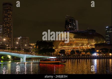 L'Esplanade Theatre la nuit avec un bateau touristique passant sous le pont Jubilee Banque D'Images