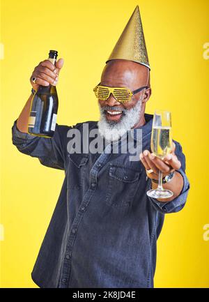 Venez vous amuser. Portrait d'un homme joyeux qui célèbre et boit du champagne en studio sur fond jaune. Banque D'Images