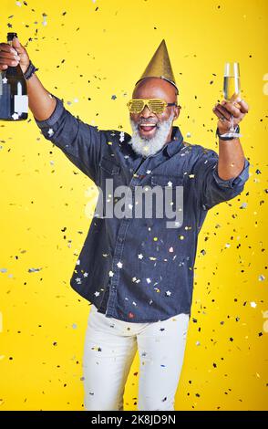 Son temps de fête. Portrait d'un homme joyeux qui célèbre et boit du champagne en studio sur fond jaune. Banque D'Images