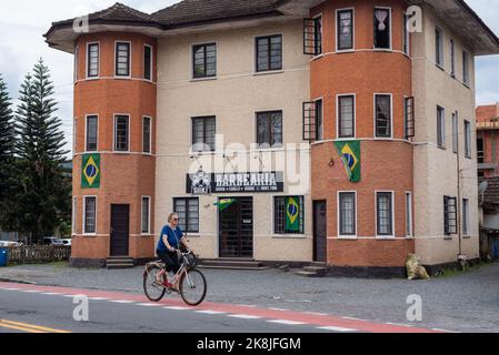 Pomerode, Brésil. 27th septembre 2022. Une femme passe son vélo devant une maison avec des drapeaux brésiliens sur la façade. Le drapeau brésilien, autrefois symbole de l'amitié entre l'Allemagne et le Brésil, représente maintenant le soutien du gouvernement actuel du Président Bolsonaro. Credit: Henry Milleo/dpa/Alay Live News Banque D'Images