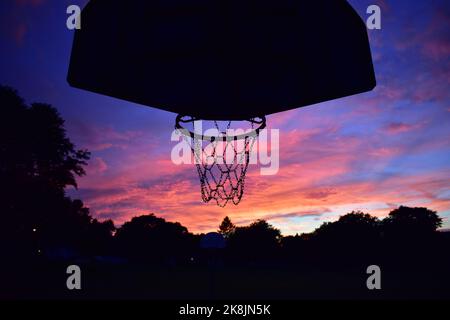 Une silhouette d'un panier de basket-ball contre un ciel nuageux et coloré au coucher du soleil Banque D'Images
