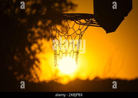 Une silhouette d'un panier de basket-ball contre un ciel doré pendant le coucher du soleil Banque D'Images