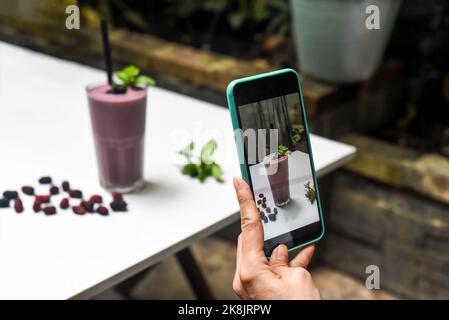 Une femme prenant des photos de smoothie aux mûres pour la publicité et les médias sociaux Banque D'Images