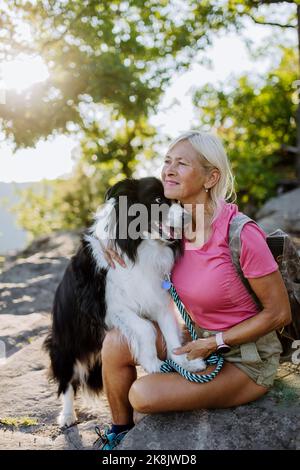 Femme sénior et trainant son chien pendant la marche dans la forêt. Banque D'Images