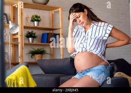 Femme enceinte souffrant pendant sa grossesse, avec des maux de dos et des maux de tête. Banque D'Images