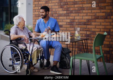 Soignant prenant le petit déjeuner avec son client au café. Banque D'Images