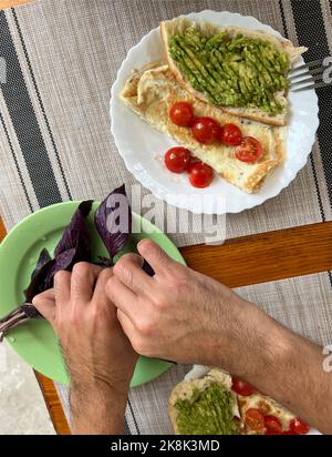 Omelette frite avec tomates, oignons et herbes. Délicieux petit déjeuner avec œufs et toasts. Banque D'Images