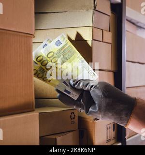 Euro argent entre les mains d'un ouvrier d'entrepôt. Paiement de la livraison des marchandises et financement dans la logistique du transport des marchandises. Banque D'Images