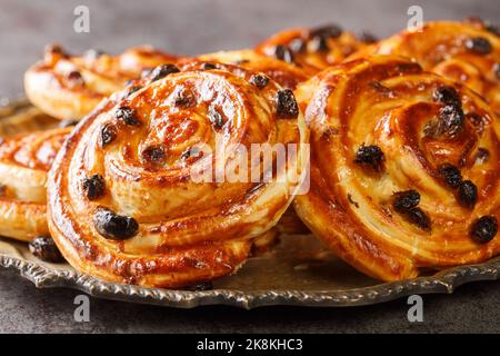 Délicieux pains aux raisins en spirale avec raisins secs et crème anglaise dans une assiette sur la table. Horizontal Banque D'Images