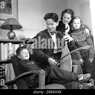 Oslo 19550212 - au domicile de l'auteur et critique de film Sigurd Evensmo. Il est ici assis avec l'instrument 'Gusle' qui est un cadeau de la compagnie de film yougoslave. V. Fils Ivar Evensmo, femme Randi Evensmo et fille Anne Marie Evensmo. Photo: Aage Storløkken / actuel / NTB Banque D'Images