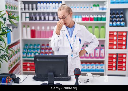 Jeune femme caucasienne travaillant à la pharmacie pharmacie fatigué frottant le nez et les yeux sensation de fatigue et de maux de tête. Concept de stress et de frustration. Banque D'Images