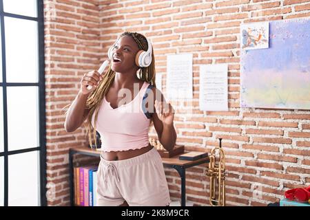 Femme afro-américaine écoutant de la musique chantant à la maison Banque D'Images