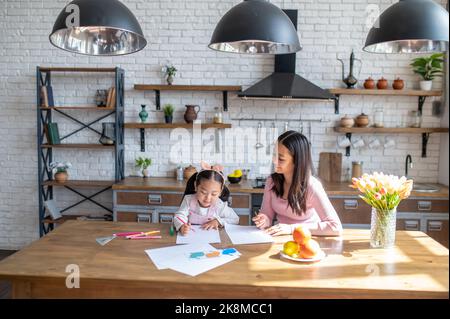 Bonne jeune maman regardant son enfant participer au dessin Banque D'Images