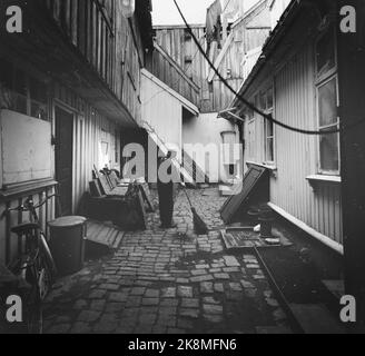 Fredrikstad 19590530 'Touristidyll from 1567' la seule ville forteresse préservée de la région nordique - construite dans l'Umbrella, aujourd'hui une grande et paisible idyll - est située à Fredrikstad. La vieille ville. Dans des portes sombres sur des charnières en fer rouillé, il cache partout une petite cour, pavée comme les rues, et avec un poteau d'eau, des crochets sombres et un escalier sournois. Dans le grenier à gauche de cette ferme il y avait autrefois un atelier de tailleur. Homme avec la nourriture qui balaie. Photo; Aage Storløkken / actuel / NTB NB! Photo non traitée ! Banque D'Images