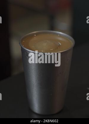 Une photo verticale d'un thé glacé au lait de style Hong Kong dans une tasse de métal. Banque D'Images